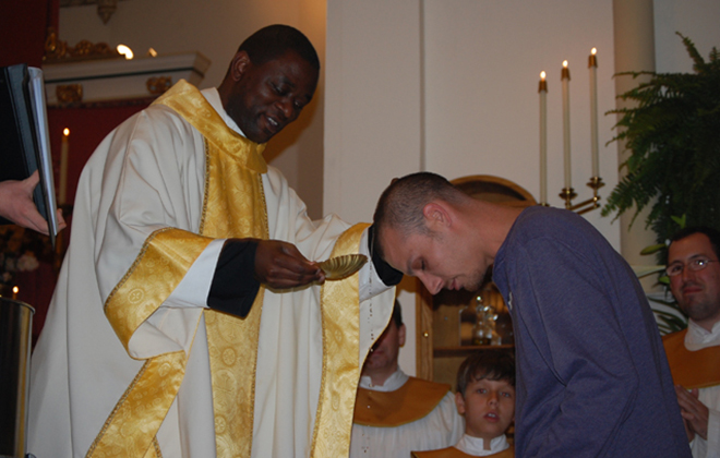 Previous pastor, Fr. Joseph Wamala, baptizes a catechumen at the Easter Vigil.
