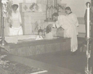 Father Abe administers a baptism in the immersion pool before its removal in 1994
